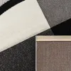 A close-up view of a rug with a geometric pattern in black, white, and gray. The backing of the rug is also visible. Anteprima dell’immagine prodotto