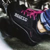 A person's foot wearing a black Sparco shoe with pink laces is pressing a metal pedal. Produktbild-Vorschau