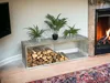 A modern living room with a fireplace, a TV, plants, and a firewood rack. Produktbild-Vorschau