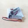 Two lithium batteries with wires and connectors are laid out on a light-colored wooden surface, with some printed instructions underneath. Náhled obrázku produktu