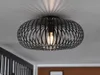 A black, cage-like ceiling light fixture with a visible light bulb is mounted on a white ceiling. The light casts a radial shadow pattern on the ceiling. Náhled obrázku produktu