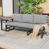 An outdoor living space with a gray sofa and a small side table. Produktbild-Vorschau