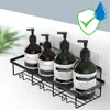 Four pump bottles of soap or lotion are displayed on a black metal shower caddy mounted on a tiled wall. A green shield with a checkmark and a blue water droplet are overlaid in the top right corner. Náhled obrázku produktu