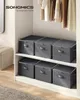 Storage boxes are neatly stacked on shelves inside a closet, with clothes hanging above. Náhľad obrázku produktu