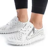 A close-up shot of a pair of white perforated leather sneakers worn by a person. Voir les images du produit