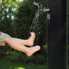 A child's feet are being rinsed under a faucet outdoors. Produktbild-Vorschau