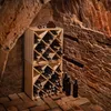 A wine cellar with brick walls and a wooden wine rack filled with bottles. Voir les images du produit