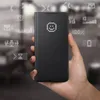 A hand holds a black smartphone with a flip cover that displays a smiley face made of dots. Various icons and graphics made of dots are displayed around the phone. Náhled obrázku produktu