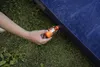 A hand is inserting an orange pump into a blue air mattress on the grass. Podgląd zdjęcia produktu