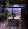 An outdoor patio scene at dusk with a floor lamp, seating, and a coffee table. Produktbild-Vorschau