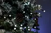 A close-up view of a decorated Christmas tree with lights and pinecones. Produktbild-Vorschau