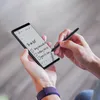 A person is using a stylus to write on a smartphone screen, which displays a to-do list. Podgląd zdjęcia produktu