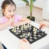 A young girl and an adult are playing chess at a table. Produktbild-Vorschau