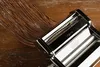 A close-up view of a pasta maker with linguine strands emerging from it, placed on a wooden surface. Anteprima dell’immagine prodotto