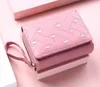 A pink wallet with a heart pattern is placed on a pink surface. Anteprima dell’immagine prodotto