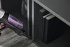 A close-up shot of a vacuum cleaner being used to clean next to a bookshelf. Voir les images du produit