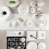 A collection of white porcelain tableware arranged on a white tablecloth. Produktbild-Vorschau