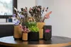 A collection of decorative vases with dried flowers and greenery arranged on a dark, round table. Produktbild-Vorschau