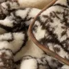A close-up view of a folded wool blanket with a brown trim. Produktbild-Vorschau