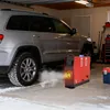A red diesel heater is positioned next to a silver SUV in a garage, with snow on the ground and smoke coming from the car's exhaust. Náhled obrázku produktu
