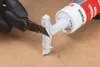 A gloved hand is using a utility knife to cut a plastic nozzle from a tube of Würth adhesive. Produktbild-Vorschau