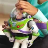A child's hands are adjusting the helmet of a Buzz Lightyear action figure. Voir les images du produit