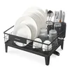 A black dish drying rack filled with white plates, glasses, and cutlery, set against a white background. Produktbild-Vorschau