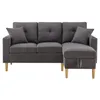 A dark gray sectional sofa with wooden legs and two throw pillows is shown against a white background. Podgląd zdjęcia produktu