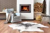 A cozy living room scene with a fireplace, armchair, and a cowhide rug. Voir les images du produit