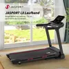 A treadmill is shown in a room with a large window overlooking a garden. Produktbild-Vorschau