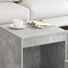 A close-up view of a concrete-gray side table with a white cup of liquid and a magazine on top, next to a white sofa. Náhled obrázku produktu