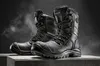 A pair of black insulated winter work boots are displayed on a concrete surface against a dark, textured background with a hint of mist. Podgląd zdjęcia produktu