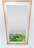 A skylight window with a light gray roller blind partially covering the view of green trees outside. Náhľad obrázku produktu