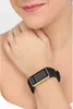 A close-up shot of a woman's wrist wearing a black and gold fitness tracker watch. Produktbild-Vorschau