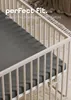 A close-up view of a crib with a fitted sheet, with text overlay. Produktbild-Vorschau