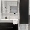 A clean, modern bathroom sink area with white subway tiles and black accents. Produktbild-Vorschau