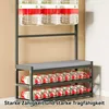 A multi-tiered storage rack filled with bottles of water, with a padded seat on the middle tier. The rack is dark gray and the bottles have red and white labels. Produktbild-Vorschau