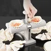 A person is using a dumpling maker to create dumplings. Several finished dumplings are visible on plates. Podgląd zdjęcia produktu