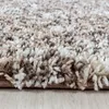 A close-up view of a shaggy rug with a beige, brown, and white speckled pattern. Produktbild-Vorschau