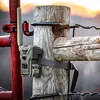 A trail camera is mounted on a wooden post with a wire fence in the background. Náhled obrázku produktu