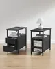 Two dark gray bedside tables are placed against a light gray wall, on a light wood floor. Náhled obrázku produktu