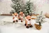 Three plush reindeer toys are arranged in a snowy winter scene with miniature Christmas trees and a sled. Produktbild-Vorschau