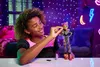 A young girl is playing with a doll in a room decorated with neon lights. Náhľad obrázku produktu