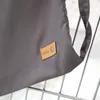 A close-up of a gray fabric product with a brown leather tag. Anteprima dell’immagine prodotto