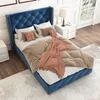 A bedroom scene with a blue upholstered bed. Produktbild-Vorschau