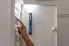 A person is using a HAZET LED pen light to examine a fuse box with a checklist attached to the inside of the door. Náhled obrázku produktu