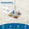 A beach umbrella table with drinks and fruit on a sandy beach. Náhled obrázku produktu