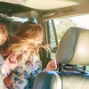 Two young women in the back seat of a car, one with her hair flying, with a car headrest mount visible. Anteprima dell’immagine prodotto
