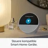 A smart speaker is placed on a table next to a lamp and perfume bottle, displaying a smart home control interface. Produktbild-Vorschau