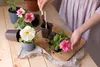 A person is shown repotting flowers on a wooden table. Produktbild-Vorschau